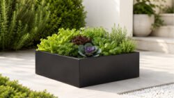 Schwarzer, niedriger Pflanzkübel Alessio 12 aus Aluminium mit Salat, Kräutern und dekorativem Kohl auf einer hellen Gartenterrasse