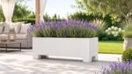 Weiße Apollo 15 Mobile Pflanzkübel aus Aluminium mit rechteckigen Standfüßen, bepflanzt mit üppiger Lavendelblüte auf einer hellen Gartenterrasse neben einem eleganten Pavillon