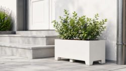 Weißer Apollo 20 Pflanzkübel aus Aluminium neben einer Außentreppe, bepflanzt mit einem kleinen Beerenstrauch