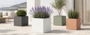 Blog 57 Quadratischer Pflanzkübel aus Fiberglas in Weiß auf einer modernen Terrasse, bepflanzt mit Lavendel und kombiniert mit drei weiteren Pflanzkübeln in unterschiedlichen Farben